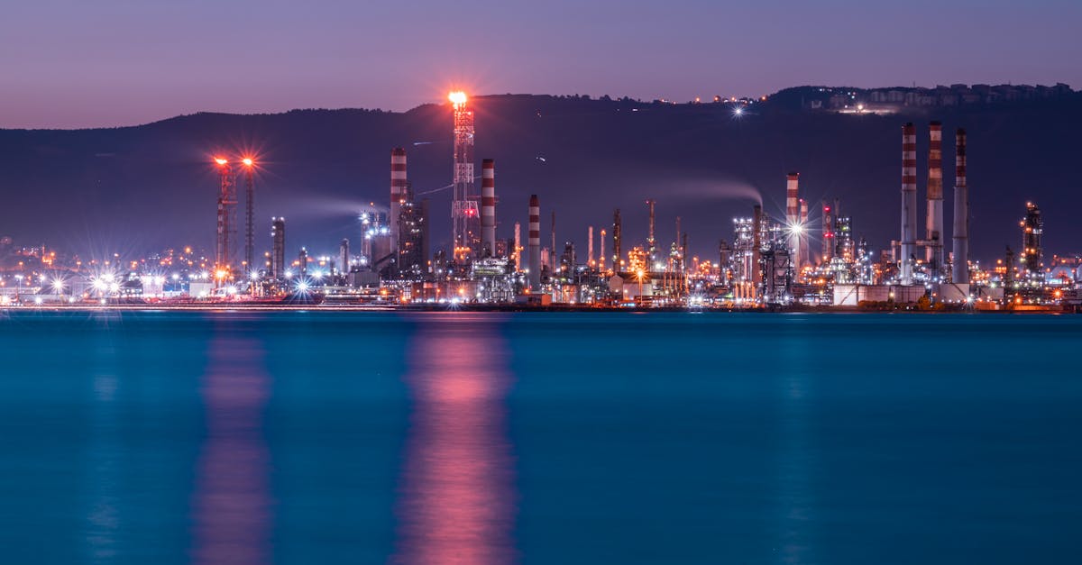 Raffinerie de pétrole illuminée la nuit au bord de la mer